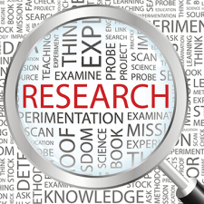 Magnifying glass over page full of words with "research" standing out in red