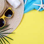 Straw hat, sunglasses, sunscreen, a blue towel, a starfish, and palm fronds on a yellow background