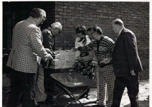 Group of men and women ceremoniously adding cement to a 1975 cornerstone of brick building