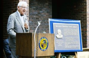 William K. Sanford speaking at podium next to his dedication plaque